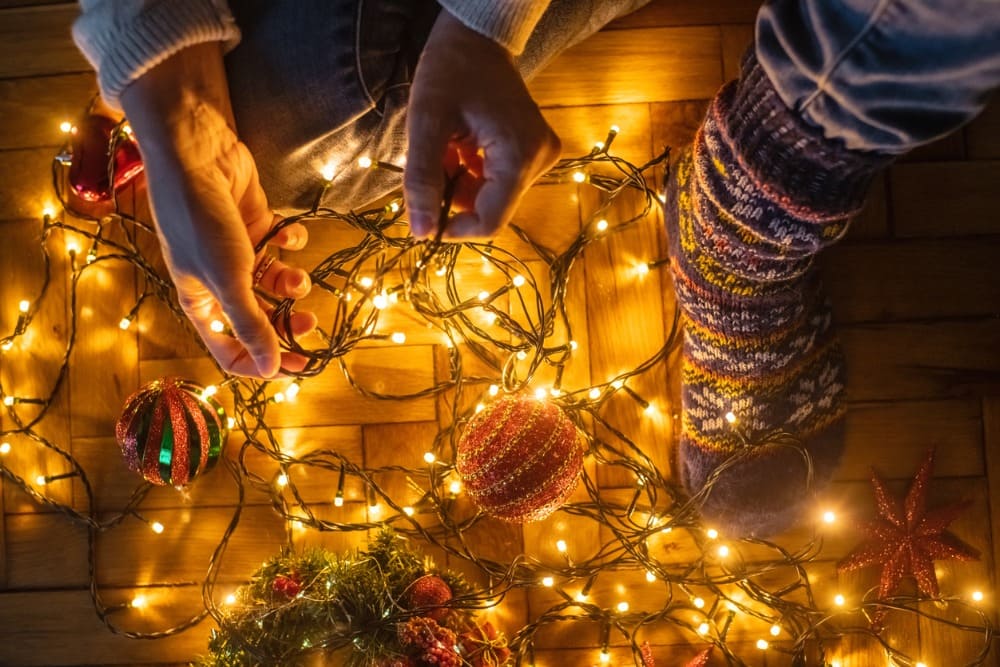 Hombre coloca las luces navideñas en el suelo junto a unas bolas de Navidad