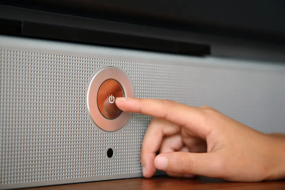 una mano está pulsando un botón de televisión con un símbolo de apagado